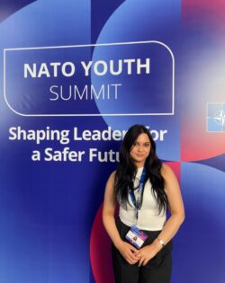 chloe simpson in front of a nato youth summit banner
